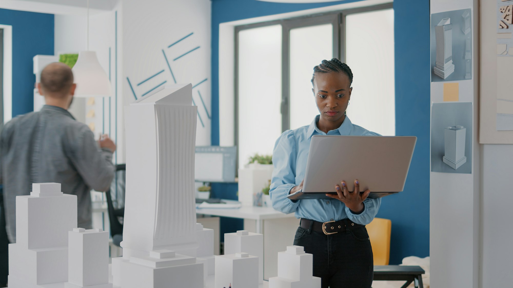 Woman engineer working on laptop to plan contruction layout with building model and maquette