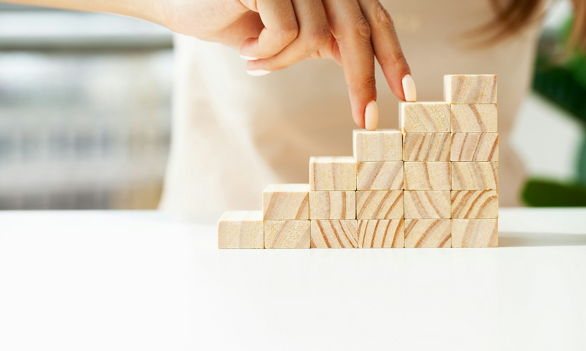 Woman hand stepping up wood block stacking as step stair