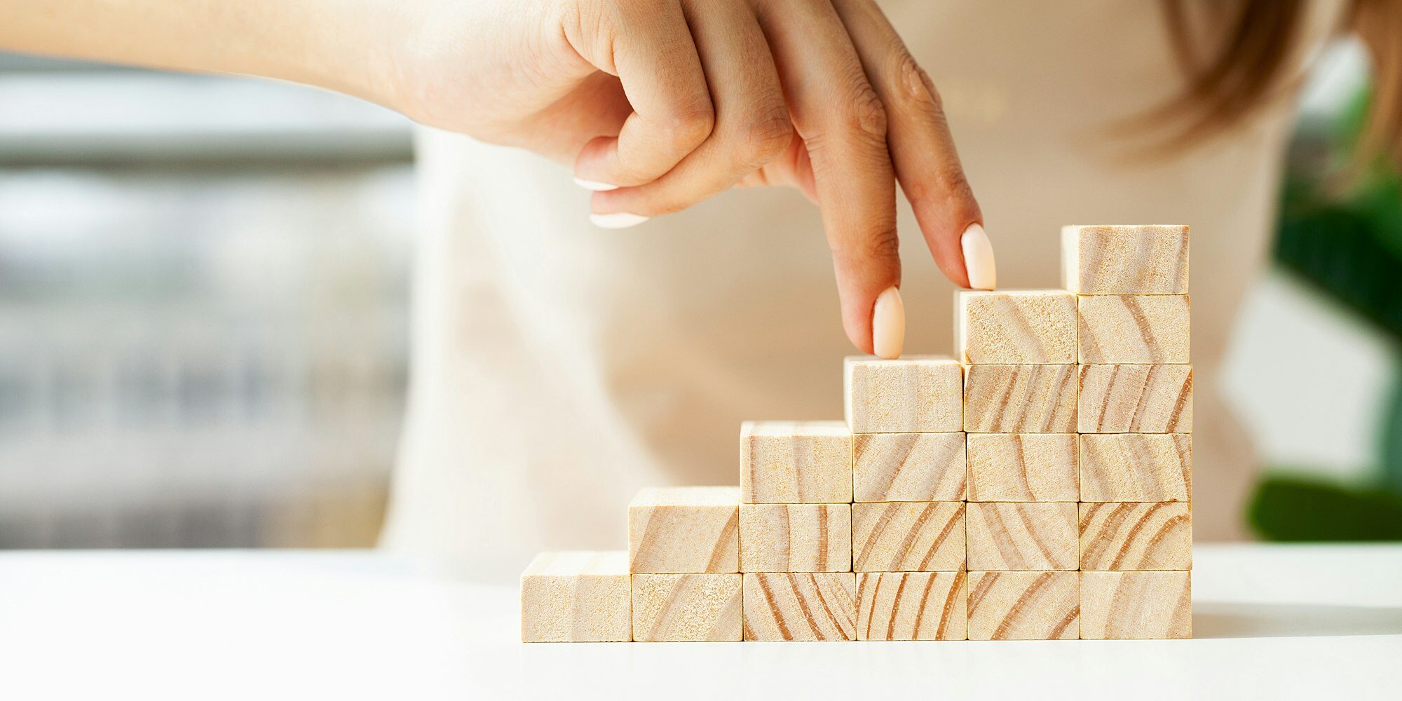 Woman hand stepping up wood block stacking as step stair